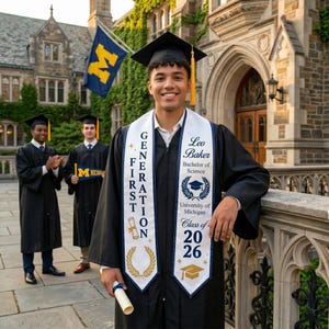 May include: A graduate in a black cap and gown, wearing a white sash with text, poses in front of a university building. The sash reads "Leo Baker, Bachelor of Science, University of Michigan, Class of 2026." Two other graduates are visible in the background.