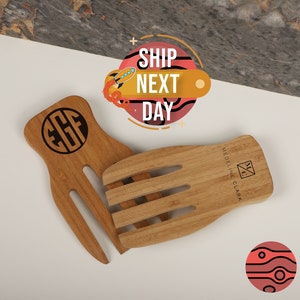 May include: A set of two wooden salad servers with a personalized monogram. The servers are made of natural wood and have a simple, elegant design. The servers are perfect for serving salads, pasta, and other dishes.