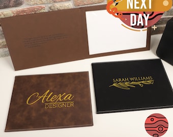 May include: Three personalized leather folders with different designs. The first folder is brown with a quote about taking risks. The second folder is brown with the name "Alexa Designer" in gold lettering. The third folder is black with the name "Sarah Williams" and a gold leaf design.