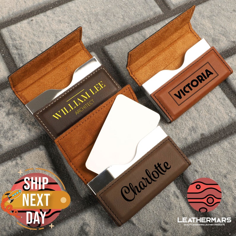 May include: Three brown leather business card holders with metal inserts. The holders are engraved with the names "William Lee Architect", "Victoria", and "Charlotte".