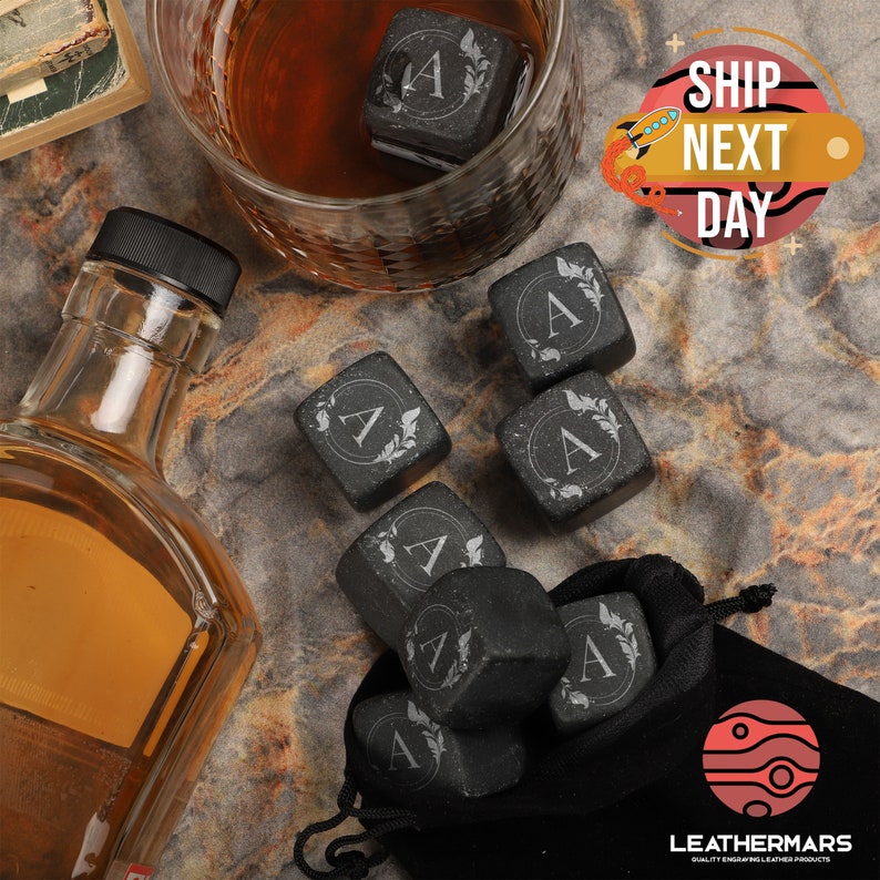 May include: Set of eight black whiskey stones with a letter A and a leaf design engraved on each stone. The stones are in a black velvet bag with a red and white logo. The text "SHIP NEXT DAY" is in a red circle with a white background.