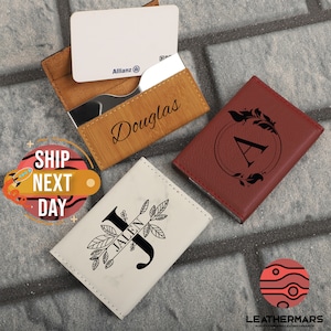 May include: Three personalized leather card holders with different designs. The first is brown with the name "Douglas" engraved on it. The second is red with a floral design and the letter "A" in the center. The third is white with a marble pattern and the letter "J" with the name "Jalen" engraved on it.