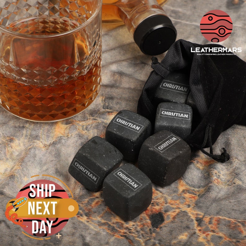 May include: Six black stone whiskey chilling cubes with the name "Christian" engraved on each cube. The cubes are in a black velvet bag.