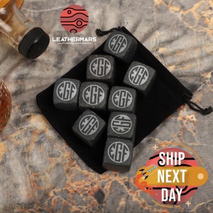 May include: Nine black granite whiskey stones with the initials "EGF" engraved on each stone. The stones are in a black velvet pouch.
