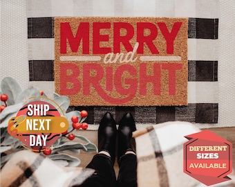 May include: A rectangular doormat with the words "MERRY and BRIGHT" in red and white lettering. The mat is made of a natural fiber material and sits on a black and white checkered rug. The image includes a pair of black boots.