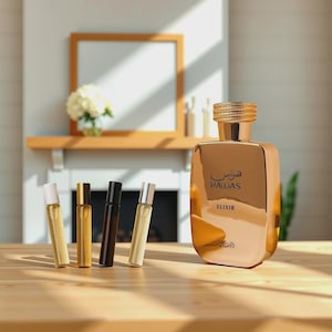 May include: A gold-colored perfume bottle and four smaller rollerball bottles are displayed on a wooden surface. The large bottle has the word "HAWAS" and "ELIXIR" printed on it. The background includes a fireplace and a decorative shelf.