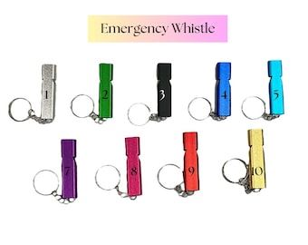 May include: A collection of ten emergency whistles in various colors, each with a keychain attachment. The whistles are numbered 1 through 10. The text "Emergency Whistle" is displayed above the whistles.