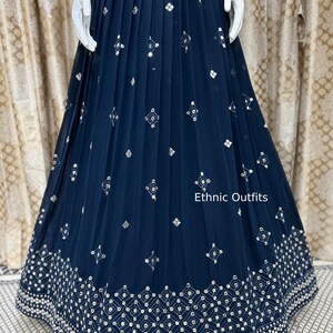 May include: Navy blue pleated skirt with intricate silver embroidery. The skirt features a detailed geometric pattern along the hemline and scattered diamond-shaped embellishments. The text "Ethnic Outfits" is visible on the image.