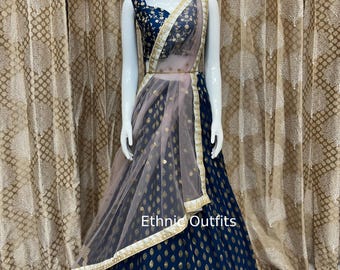 Puede incluir: Un lehenga azul marino y dorado con un dupatta de red rosa. El lehenga tiene un diseño bordado en oro y un borde de cuentas. El dupatta tiene un borde bordado en oro. El texto "Ethnic Outfits" es visible en la imagen.