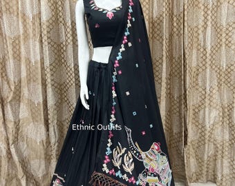 May include: Black ethnic outfit featuring a sleeveless top and pleated skirt. The outfit includes a matching shawl with colorful elephant and floral designs. The text "Ethnic Outfits" is visible on the skirt.