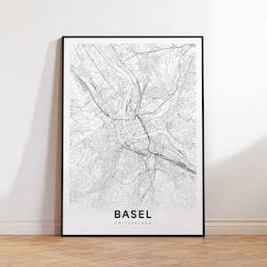 Peut inclure: Une impression encadrée en noir et blanc de la carte de Bâle, Suisse. La carte détaillée montre les rues, les cours d'eau et les infrastructures de la ville. Le mot "BASEL" est imprimé en gras, avec "SWITZERLAND" en dessous.