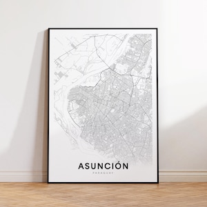 May include: A framed black and white map print of Asunción, Paraguay. The map details the city's streets and waterways. The city name is printed in bold black letters at the bottom, with "PARAGUAY" below it.