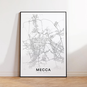 Pode incluir: Uma impressão emoldurada em preto e branco do mapa de Meca, Arábia Saudita. O mapa detalha as estradas e infraestruturas da cidade. A palavra "MECCA" é impressa em letras maiúsculas pretas em negrito, com "SAUDI ARABIA" abaixo.