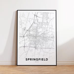 Puede incluir: Impresión de mapa de arte de línea en blanco y negro de Springfield, Ohio. El mapa muestra las calles y los puntos de referencia de la ciudad. El nombre de la ciudad está impreso debajo del mapa.