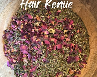 May include: A wooden bowl filled with a mixture of dried green herbs and vibrant pink rose petals. The text "Hair Renue" is written in white script across the top portion of the bowl, overlaying the botanical blend of dried plant matter.