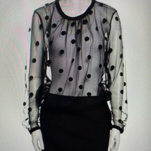 Peut inclure: Un haut noir transparent à pois et une mini-jupe noire.