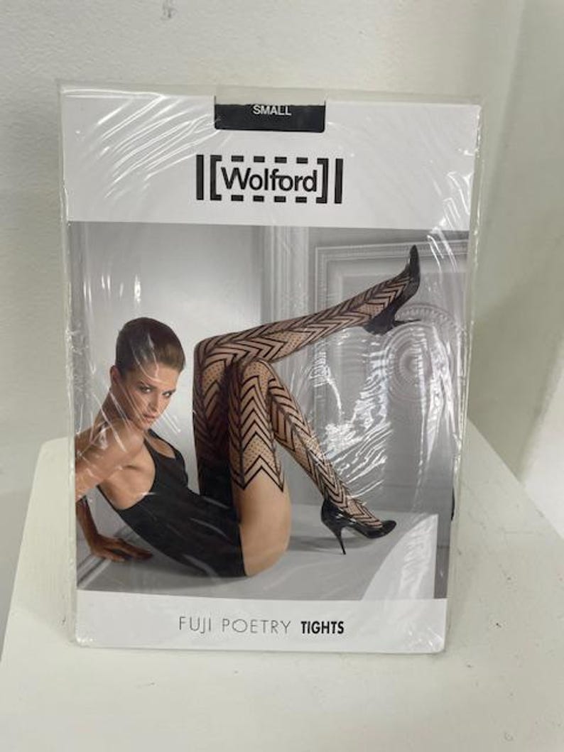 May include: A white package with black text that reads "SMALL" and "[Wolford]" on the top. The package shows a woman wearing black and white patterned tights with the text "FUJI POETRY TIGHTS" at the bottom.