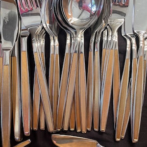 May include: A set of silver cutlery with gold-coloured handles. The set includes forks, knives and spoons.