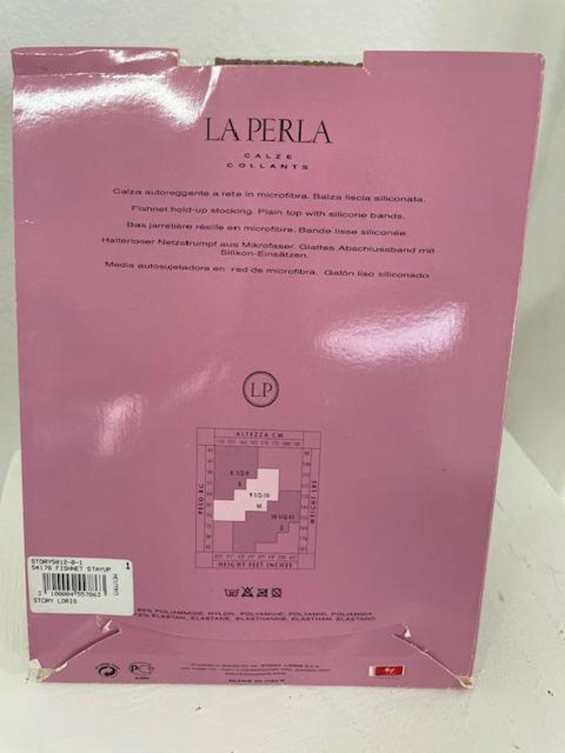 May include: Pink and white packaging for La Perla tights. The packaging features a size chart in centimeters and inches. The text on the packaging is in Italian, English, German, and Spanish. The packaging also includes a care label with washing instructions.