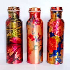 May include: Three copper water bottles with floral designs. The bottles have different patterns, including a pink and green floral design, a copper and red floral design, and a blue and gold floral design.
