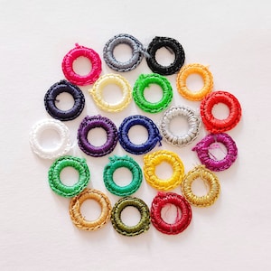 May include: Assortment of colorful embroidery hoops in various sizes, arranged in a circle pattern on a white background.