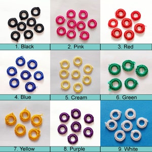 Könnte beinhalten: Neun Sätze mit jeweils zehn kleinen, gehäkelten Ringen in verschiedenen Farben: Schwarz, Rosa, Rot, Blau, Creme, Grün, Gelb, Lila und Weiß.