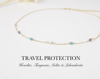 May include: A delicate gold chain necklace featuring small, evenly spaced beads of white howlite, turquoise, iolite, and labradorite. The text TRAVEL PROTECTION Howlite, Turquoise, Iolite & Labradorite is printed below the necklace.