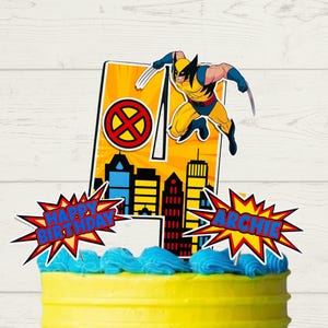 May include: A yellow birthday cake with blue icing and colourful sprinkles. The cake is decorated with a number 4 and a Wolverine superhero figure. The words "Happy Birthday Archie" are displayed on the cake.