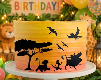 May include: A layered birthday cake with a sunset-colored gradient, decorated with black silhouettes of animals and birds. The cake sits on a white cake stand. The words "HAPPY BIRTHDAY!" are visible in the background.