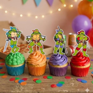 Puede incluir: Cuatro cupcakes con glaseado colorido y adornos de las Tortugas Ninja. Los cupcakes tienen glaseado verde, naranja, morado y rojo, con envoltorios a juego. Confeti colorido esparcido sobre la superficie de madera, con globos en el fondo.
