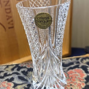 Könnte beinhalten: Transparente Kristallvase mit Rautenmuster und ausgestellter Oberseite. Die Vase trägt ein Etikett mit der Aufschrift "cristal d'arques FRANCE". Die Vase ist etwa 15 cm hoch und eignet sich zur Präsentation von Blumen oder als Dekoration.