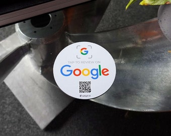 May include: White round sticker with a Google logo and a QR code. The sticker says "Tap to review on Google".