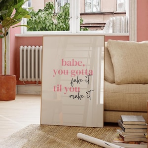 Może przedstawiać: Wydruk w ramie z różowym i czarnym tekstem nałożonym na białe tło. Tekst brzmi "babe, you gotta fake it til you make it".