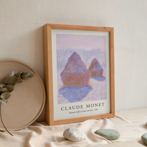 May include: A framed print of a painting by Claude Monet titled "Haystacks (Effect of Snow and Sun - 1891)". The painting depicts two haystacks in a field with a snowy background.