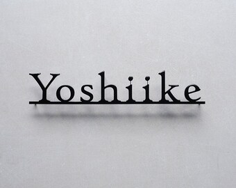 May include: Black metal sign with the name "Yoshiike" written in a stylised font.