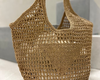 May include: A tan crocheted tote bag with a large open weave. The bag has a single handle and is made of a natural fiber.