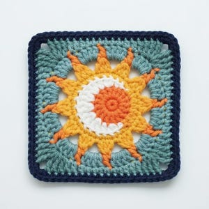 May include: A square, crocheted sun design in shades of yellow, orange, white, and blue. The sun has pointed rays and a spiral center. The square is bordered in navy blue.