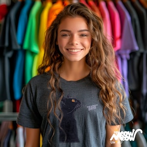 Young woman wearing a dark gray t-shirt with an illustration of a black cat. Beside the cat is the text '* BARK *'