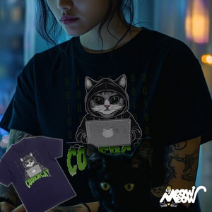 May include: A black t-shirt with a green graphic of a cat wearing a hoodie and using a laptop. The cat is surrounded by green binary code. The text "CODERCAT" is below the cat. A person is wearing the t-shirt and holding a black cat.