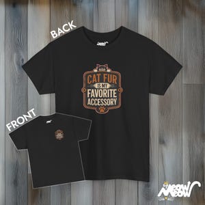 May include: Black t-shirt with a brown and orange graphic that says "Cat fur is my favorite accessory". The graphic features a cat peeking out from behind the text.