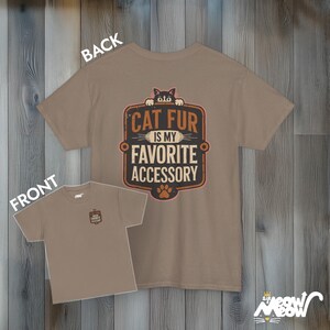 May include: A brown t-shirt with a cat peeking out from behind a sign that says "Cat fur is my favorite accessory".