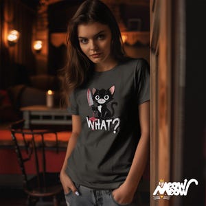 May include: A dark gray t-shirt with a black cat holding a bloody knife and the text "WHAT?" printed on the front.