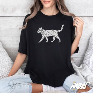 May include: Black t-shirt featuring a geometric cat design in white. The cat illustration is made up of interconnected triangles and lines, creating a modern, minimalist aesthetic. The shirt has a classic crew neck and short sleeves.