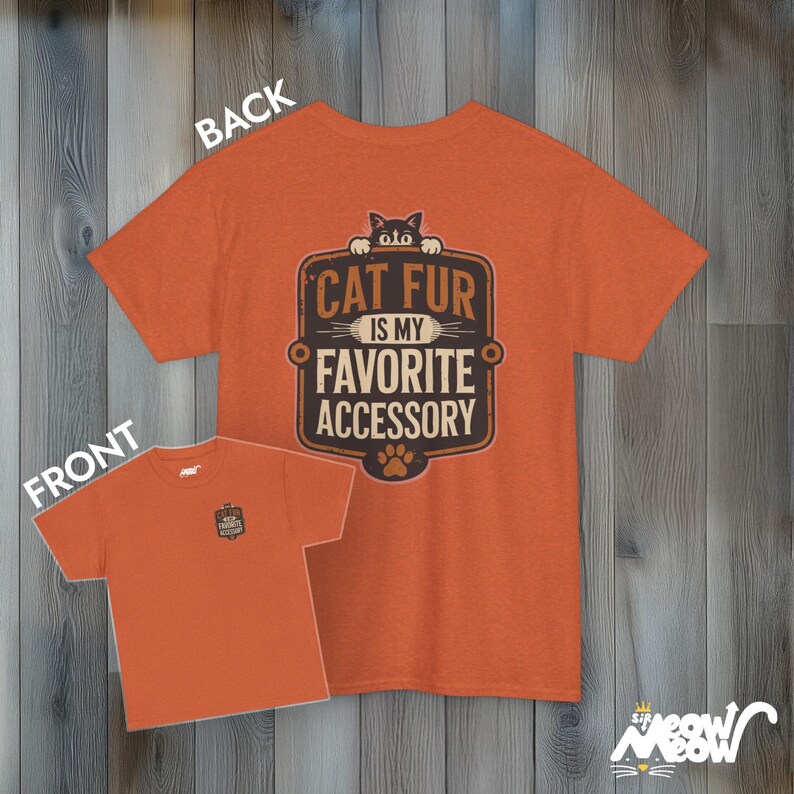 May include: Orange t-shirt with a brown and white graphic that says "Cat Fur is my Favorite Accessory". A black cat is peeking over the top of the graphic. The back of the shirt is plain orange.