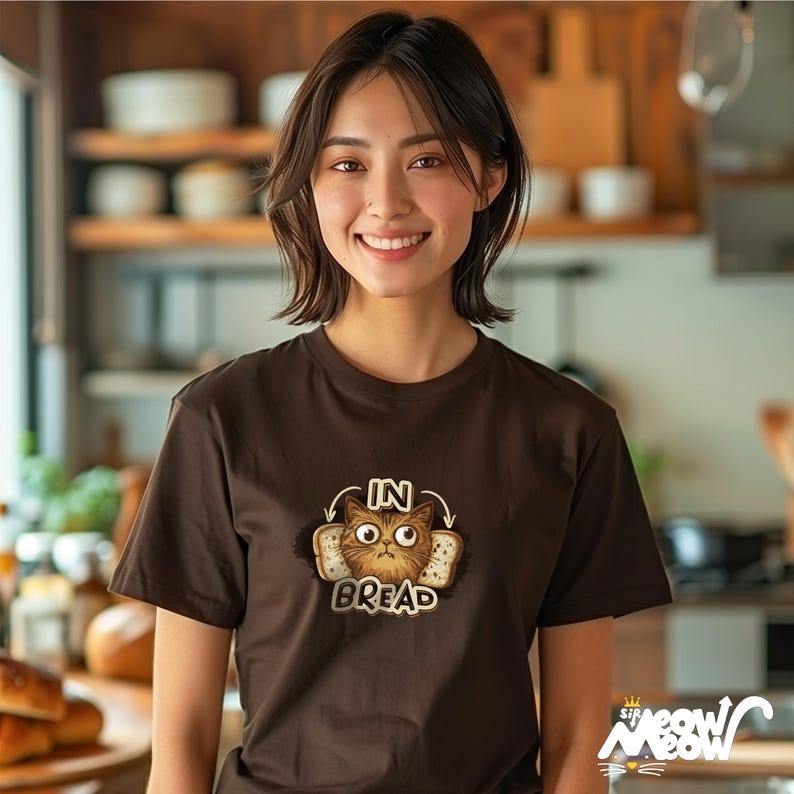 May include: A brown t-shirt with a graphic of a cat inside a slice of bread. The text "In Bread" is printed below the cat.