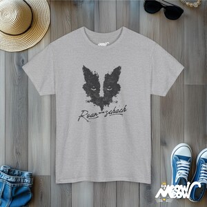 May include: A heather grey t-shirt with a black and white inkblot design of a cat's face. The text "Rorschach" is written in black below the design.