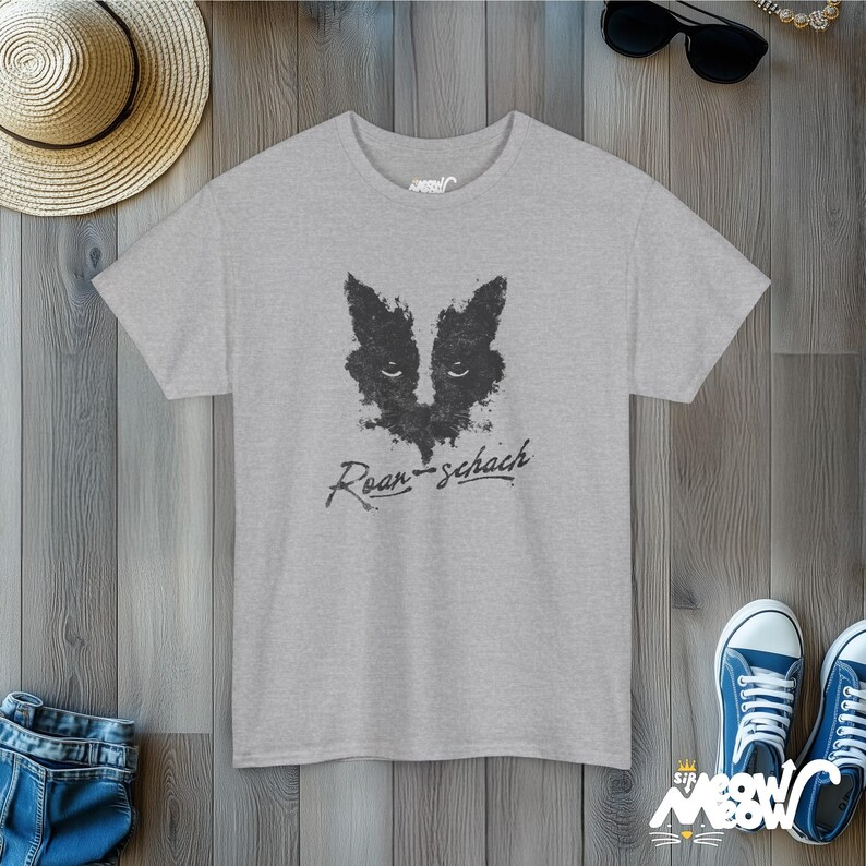 May include: A heather grey t-shirt with a black and white inkblot design of a cat's face. The text "Rorschach" is written in black below the design.