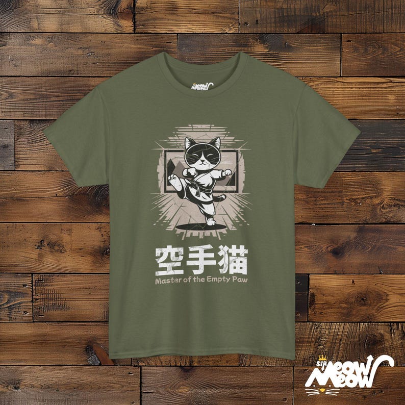 May include: A green t-shirt with a cartoon cat wearing sunglasses and a karate uniform. The cat is kicking with its right leg and the text "空手猫 Master of the Empty Paw" is printed below the image.