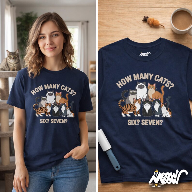 May include: Navy blue t-shirt with a graphic of several cats and the text "HOW MANY CATS? SIX? SEVEN?". The shirt features a crew neck and short sleeves. A woman is wearing the shirt in the image.