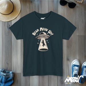 May include: A dark blue t-shirt with a graphic of a black cat being beamed up in a UFO. The text on the shirt reads "Beam Meow Up!"